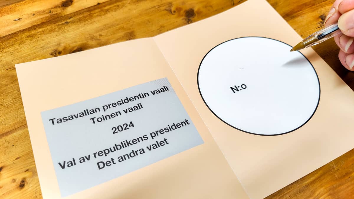 Ruskehtavan sävyinen ennakkoäänestyslappu, jossa harmaalla pohjalla teksti "Tasavallan presidentin vaali, toinen vaali 2024". Sivussa käsi, jossa kynä.