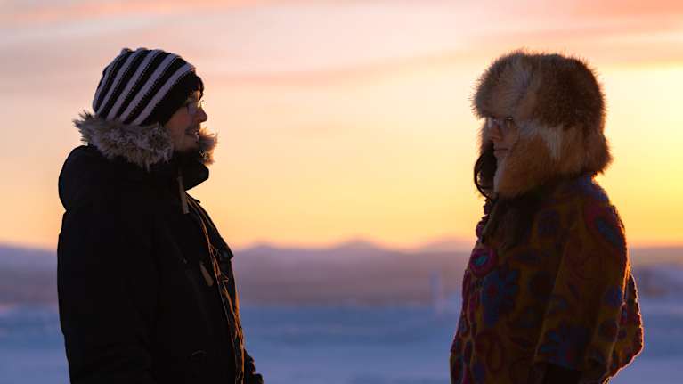 Oskari Ja Saara Adler hymyilevät Lapin maisemissa toisilleen.