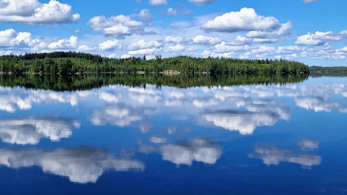 Tyyni kesäpäivä Nurmijärvellä. Pilvet heijastuvat veden pintaan. 