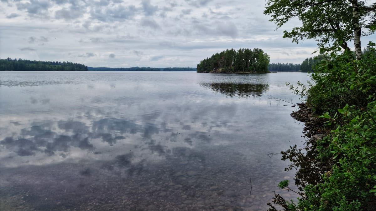 Harmaa päivä Nurmijärvellä. Järvimaisemaa, saaria ja pilviä. 