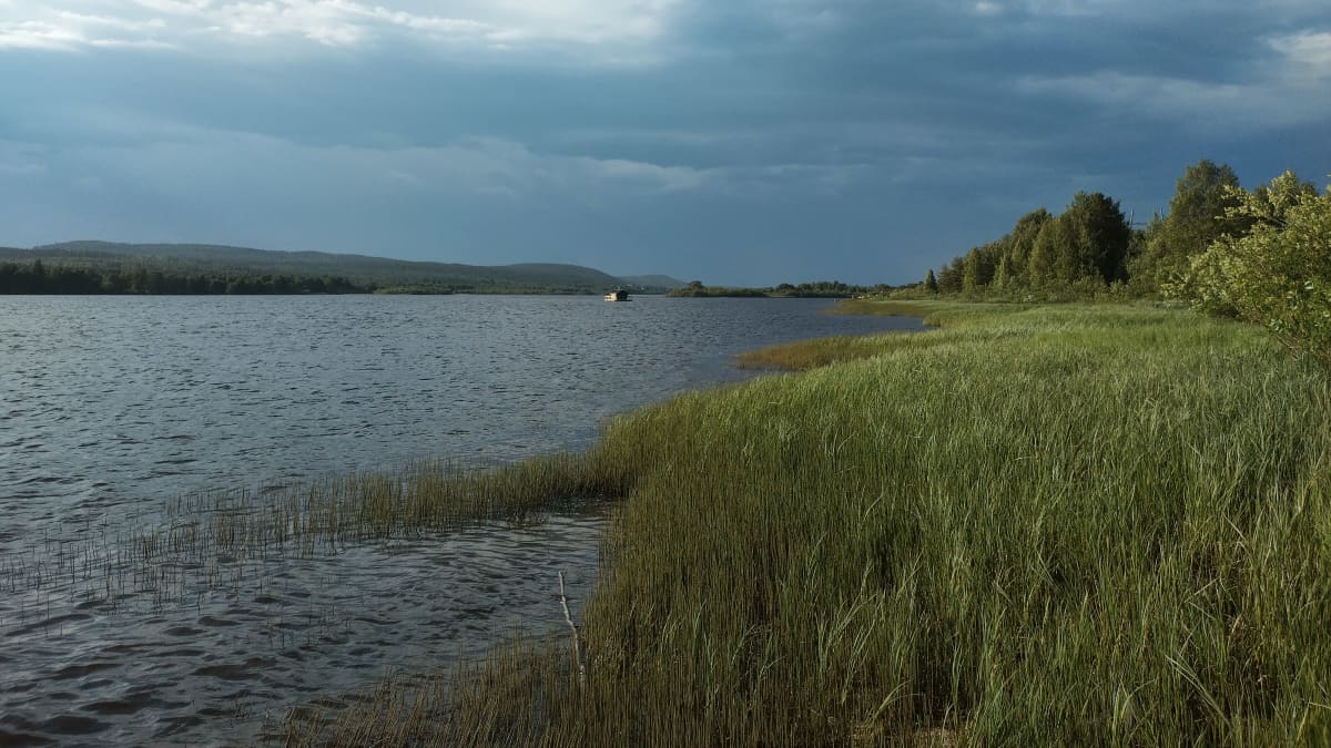 Ukkospilvi nousee Yli-Torniolla. Jokimaisema ja tumma taivas. 