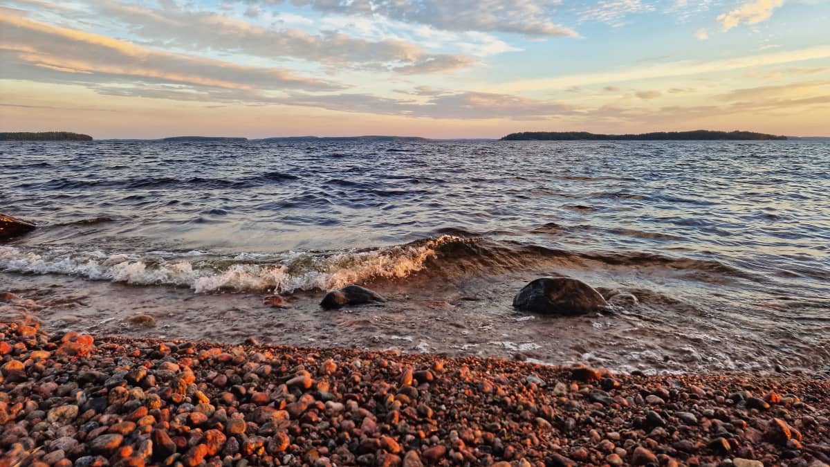 Saimaan aaltoja. Kivinen ranta johon aallot lyövät. 