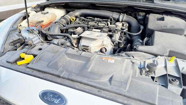 Motorn under motorhuven på en begagnad vitfärgad Ford.