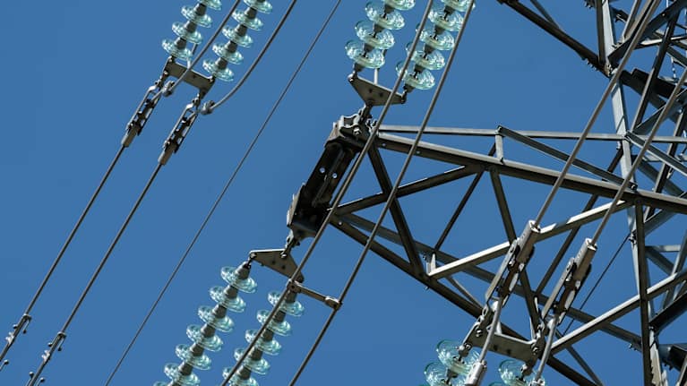 Sähkölinjoja ja niiden teräspylväissä olevia sähköeristeitä kuvattuna alhaalta ylös.