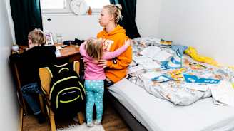 Leevi tekee tehtäviä, Miira nostaa Sofian syliin.