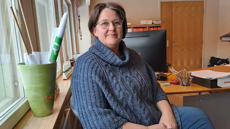Minna Boström sitter på en stol vid ett fönster.