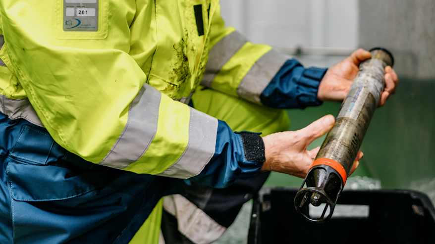 Työntekijä tarkistaa näytteen analysointia varten turvallisuusvarusteet päällä.