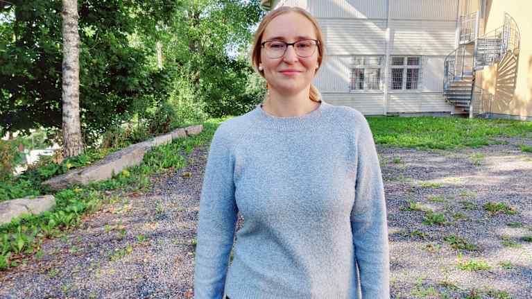 Denise Ramstedt går intill en byggnad i trä.