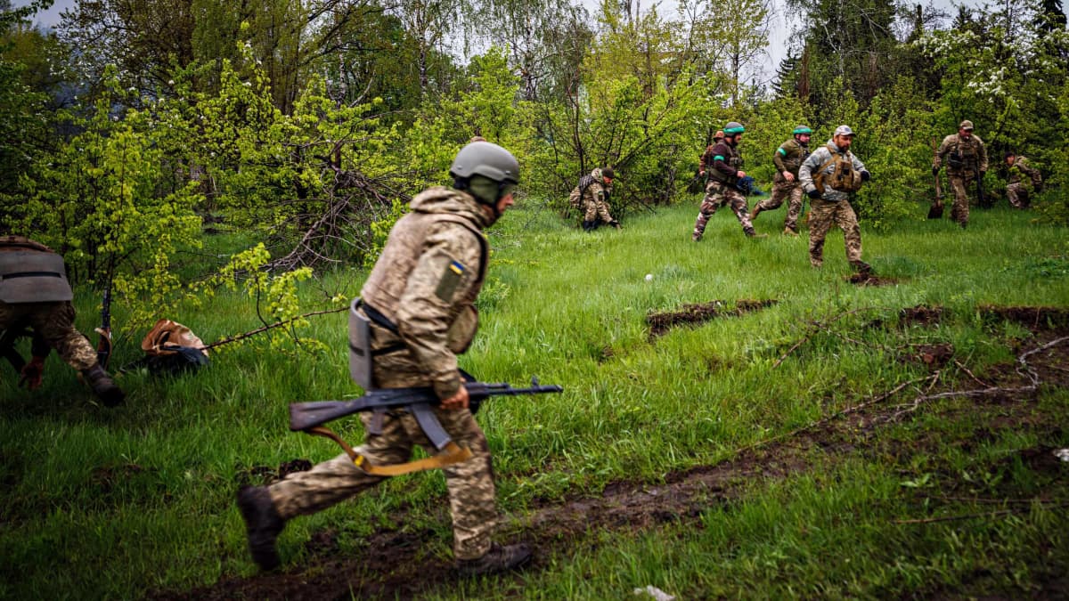 Ukrainan sotilaat juoksevat suojaan pommitusten aikana lähellä Bahmutia 30. huhtikuuta 2023.