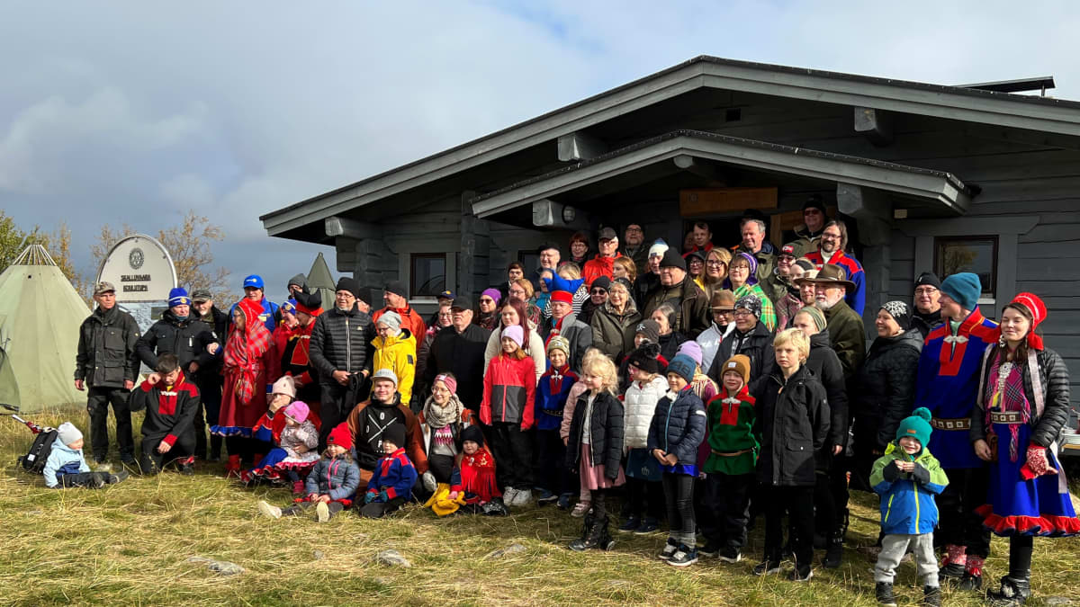 Aikuisia ja lapsia seisomassa Skalluvaaran koulutuvan edustalla.
