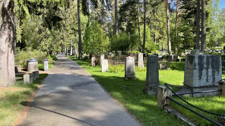 Hautakiviä ja puistokäytävä Kuopion Isolla hautausmaalla.