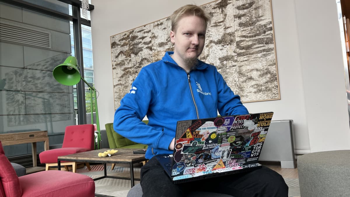 Ammattitaidon EM-kisoihin lähtevä Heikki Miinalainen istuu läppäri sylissään hotellin aulatilassa. Kannettavan tietokoneen kanssi on täynnä tarroja. Miinalaisen päällä on maajoukkueen sininen asu, jonka hihassa on Suomen lippu. 