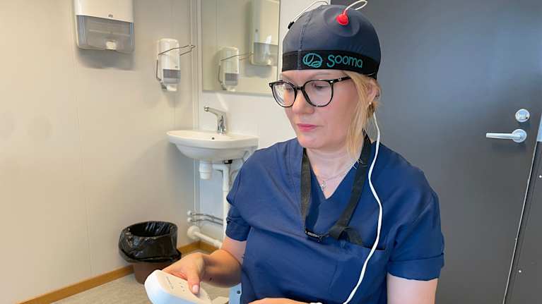 Hoitaja testaa masennuksen hoitoon käytettävää laitetta.