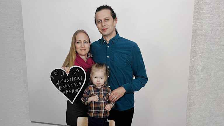 Valokuvassa on äiti, isä ja pieni lapsi.
