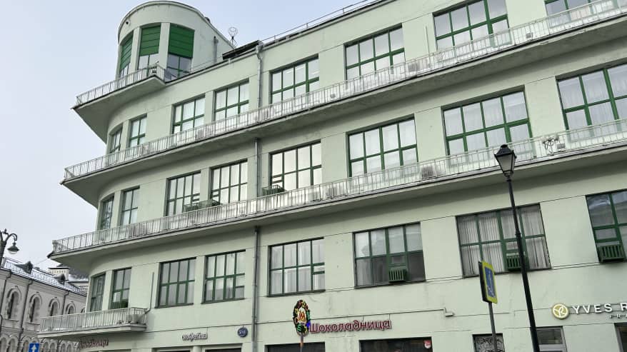 Vaaleanvihreä kerrostalo, edessä kulkee ihmisiä toppatakeissa.