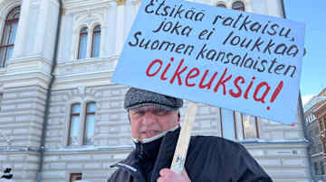 Mielenosoittaja pitää kylttiä, jossa lukee "Etsikää ratkaisu, joka ei loukkaa Suomen kansalaisten oikeuksia!"