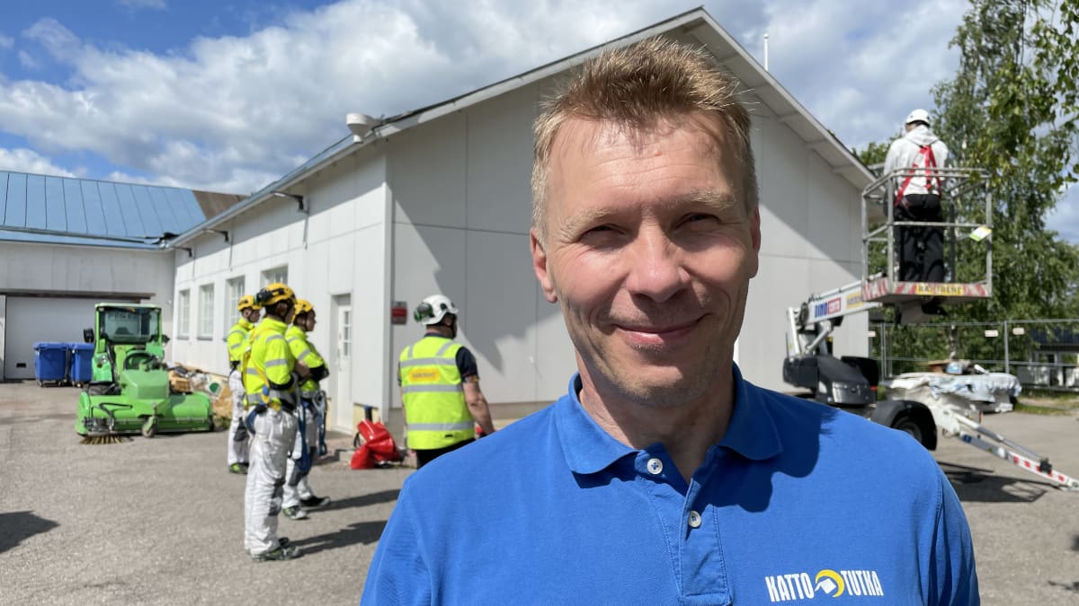 Puolipilvinen kesäsää. Etualalla sinisessä paidassa seisoo Heikki Kumpulainen. Taustalla huomiokeltaiseen pukeutuneita henkilöitä kypärissään perehtyvät henkilönostimen käyttöön.