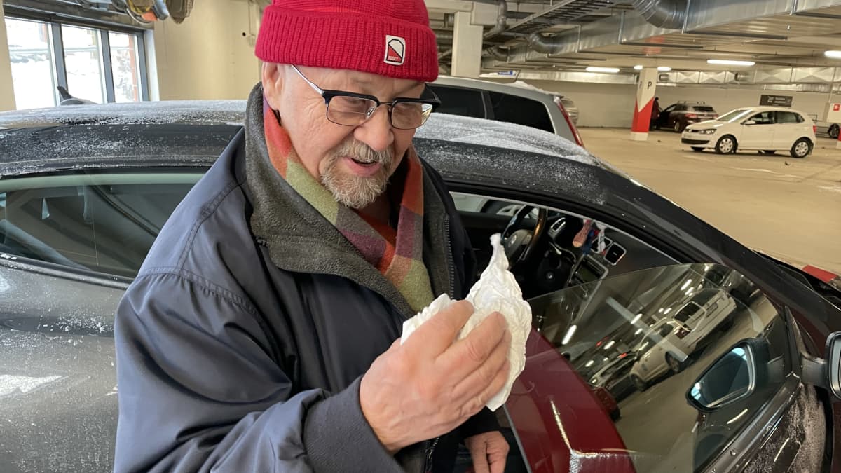 A man wipes the window of a melting car in a parking garage.