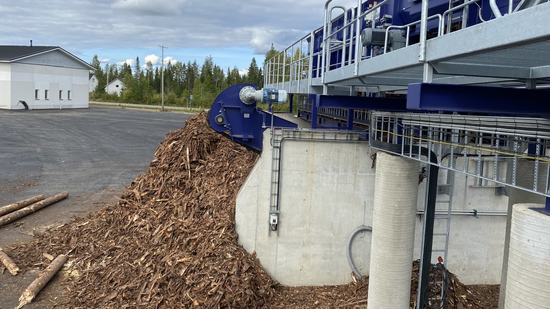 Puunhaketta iso kasa kuljettimen vieressä.