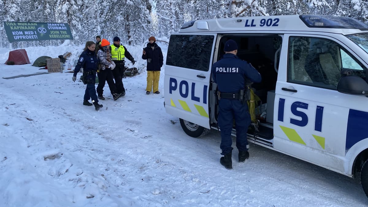 Poliisit taluttavat mielenosoittajaa poliisiautoon.