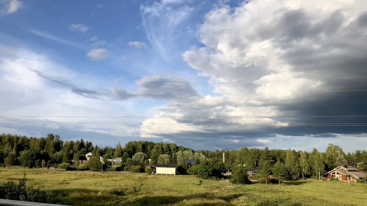 Kuvassa näkyy peltoa, metsää ja pilviä.
