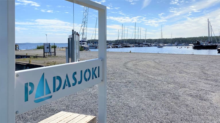 Lähikuvassa on Padasjoen venesatama kesällä. Padasjoki-kyltti on etualalla ja takana järvellä on veneitä. 