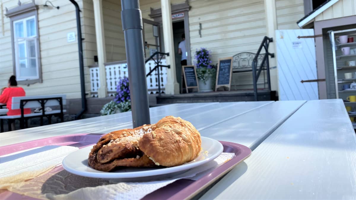 Lähikuvassa on ravintolan ulkoterassin pöytä. Pöydällä on lautanen, jossa on korvapuusti.