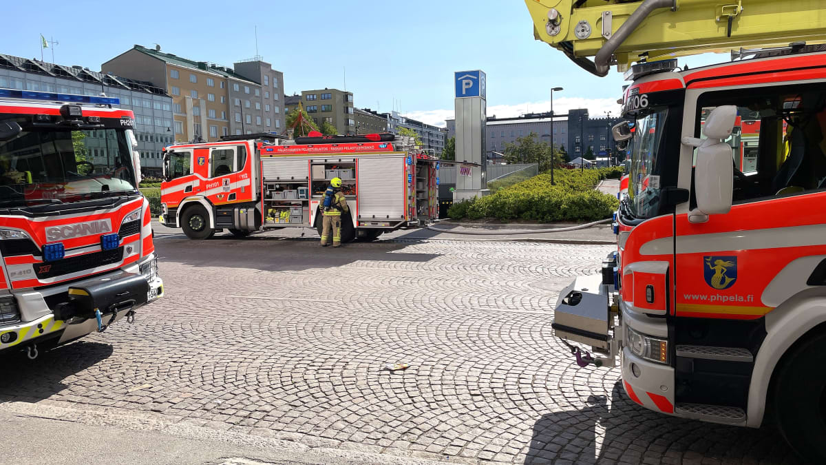 Kolme paloautoa Lahden toriparkin edustalla. Yksi palomies hommailee paloutolla.