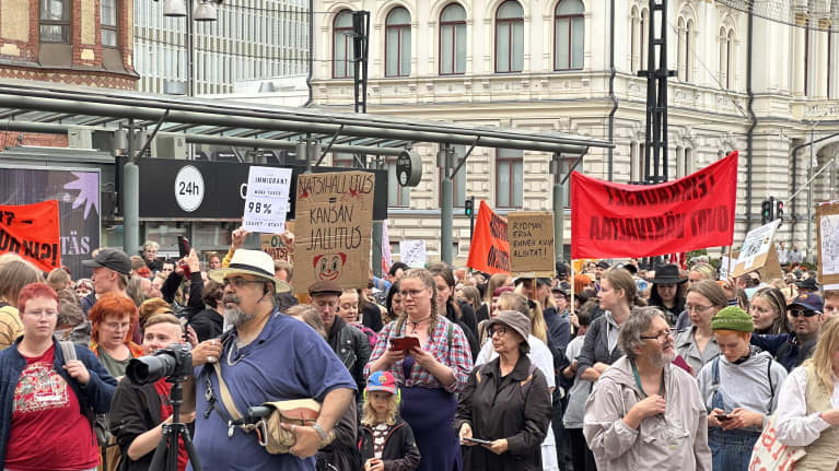 Mielenosoituskulkueeseen osallistuvilla ihmisillä on esillä useita itse tehtyjä kylttejä.