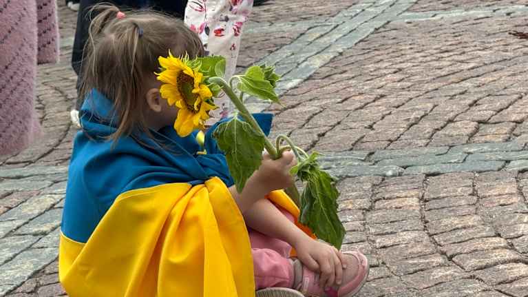 Senate Square in Helsinki. Action “United for Ukraine” for the Independence Day of Ukraine 24.08.2024.   A girl wrapped in the Ukrainian flag holding a sunflower. 