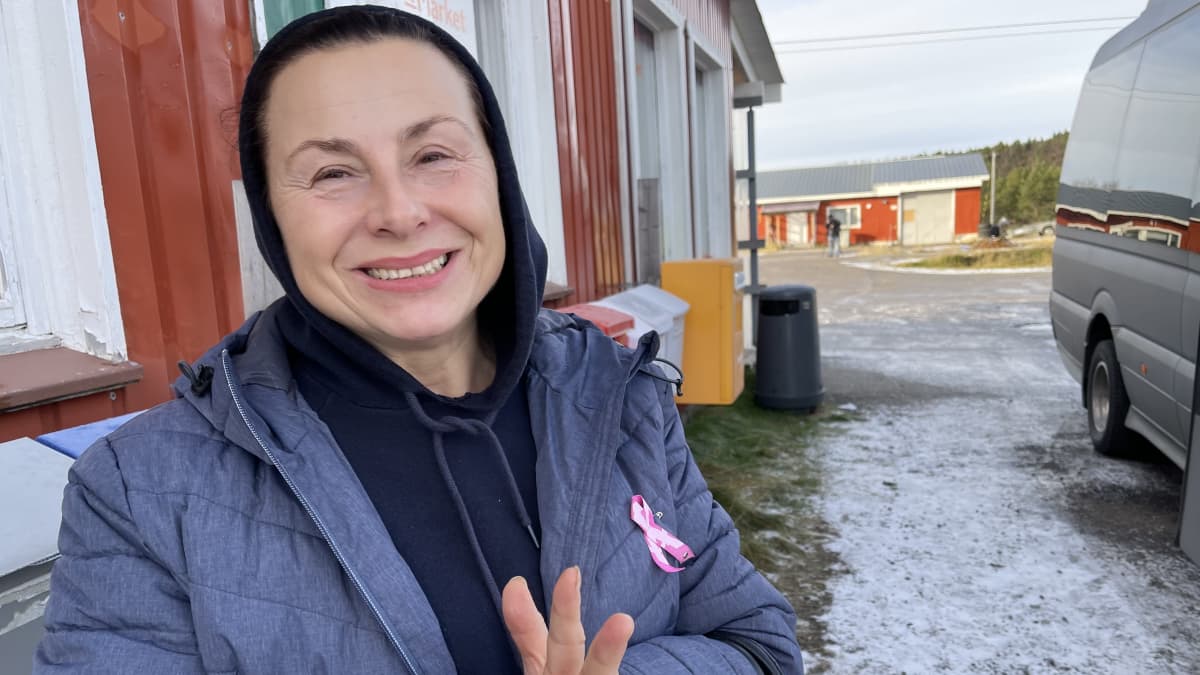 Nainen kaupan pihalla bussin vieressä