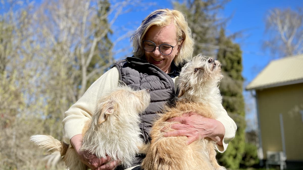 Outi Piisi holding two dogs in her lap.
