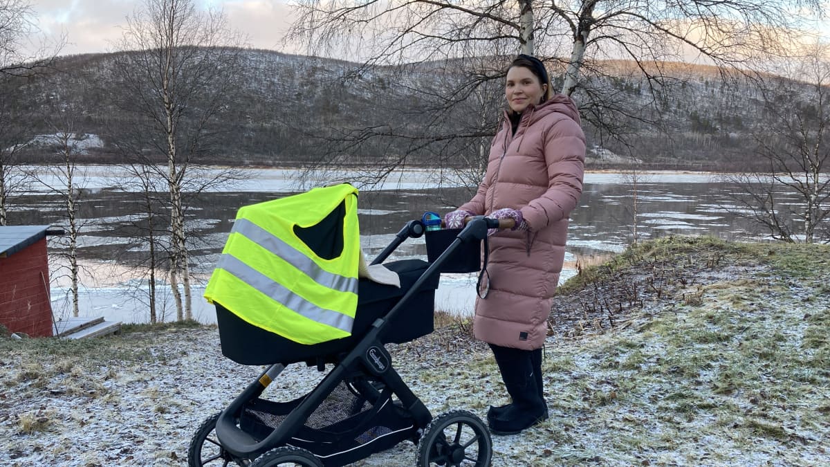 Leena Niittyvuopio-Jämsä seisoo Tenon rannalla lastenvaunujen kanssa.
