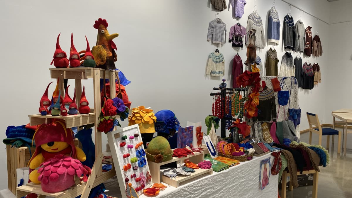 Värikkäitä tekstiilituotteita, esimerkiksi tonttuja, hattuja, villasukkia ja villapaitoja Tornion neulefestareilla.