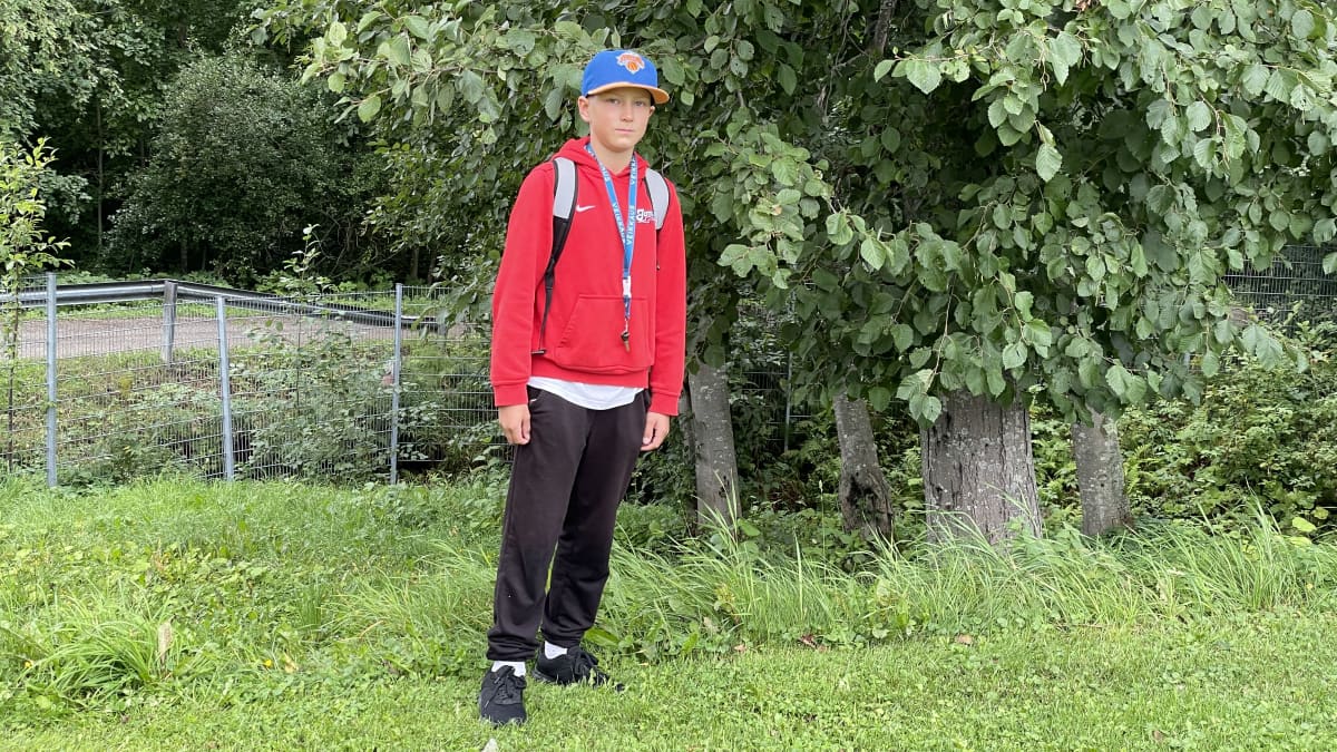 13-vuotias pesäpallon harrastaja Jesse Soininen seisoo nurmialueella ison puun vierellä.