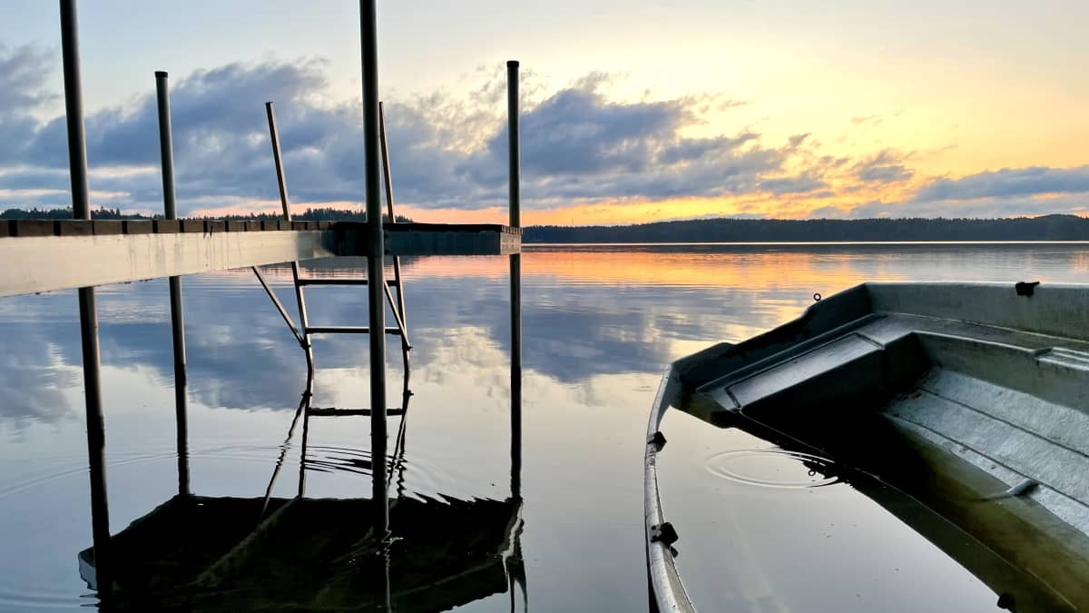 Tyyni aamu Littoistenjärven rannalla. Laituri ja vene puolillaan vettä. 
