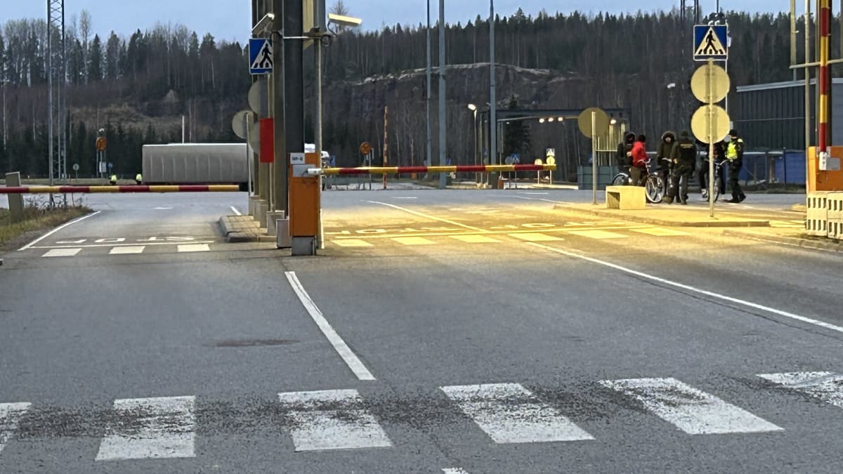 Rajaviranomaiset keskustelevat pyörillä saapuneiden turvapaikanhakijoiden kanssa Nuijamaalla Lappeenrannassa. Muuten alueella on hyvin tyhjää.