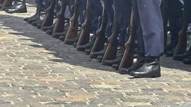 Kunniakompannian sotilaat seisovat millin suorissa riveissä uniformuissa. Mustat saappaat ja kiväärit on asetettu linjakkaasti riveihin.
