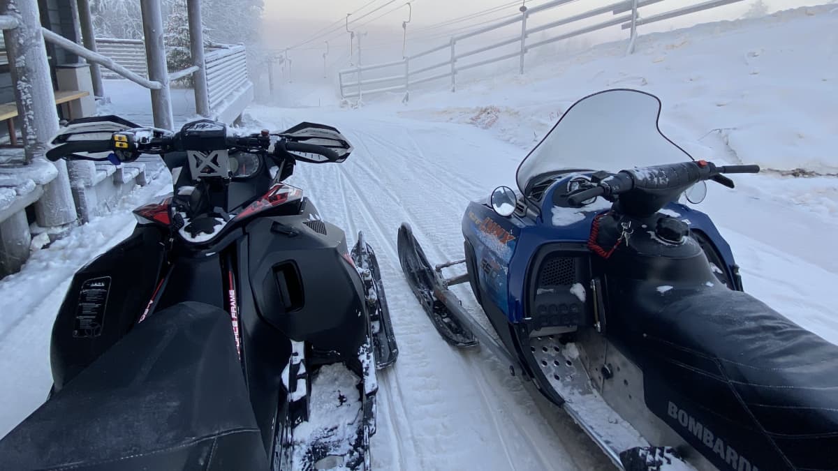 Kaksi moottorikelkkaa lumisessa maisemassa.