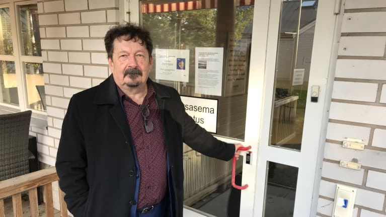Kustavin kunnanjohtaja Rauno Peltola kokeilee lukossa olevaa terveysaseman ovea.