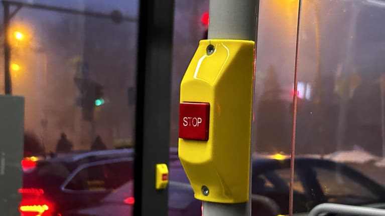 Lähikuvassa on keltainen pysäytyslaite, jossa keskellä punainen stop-nappi.