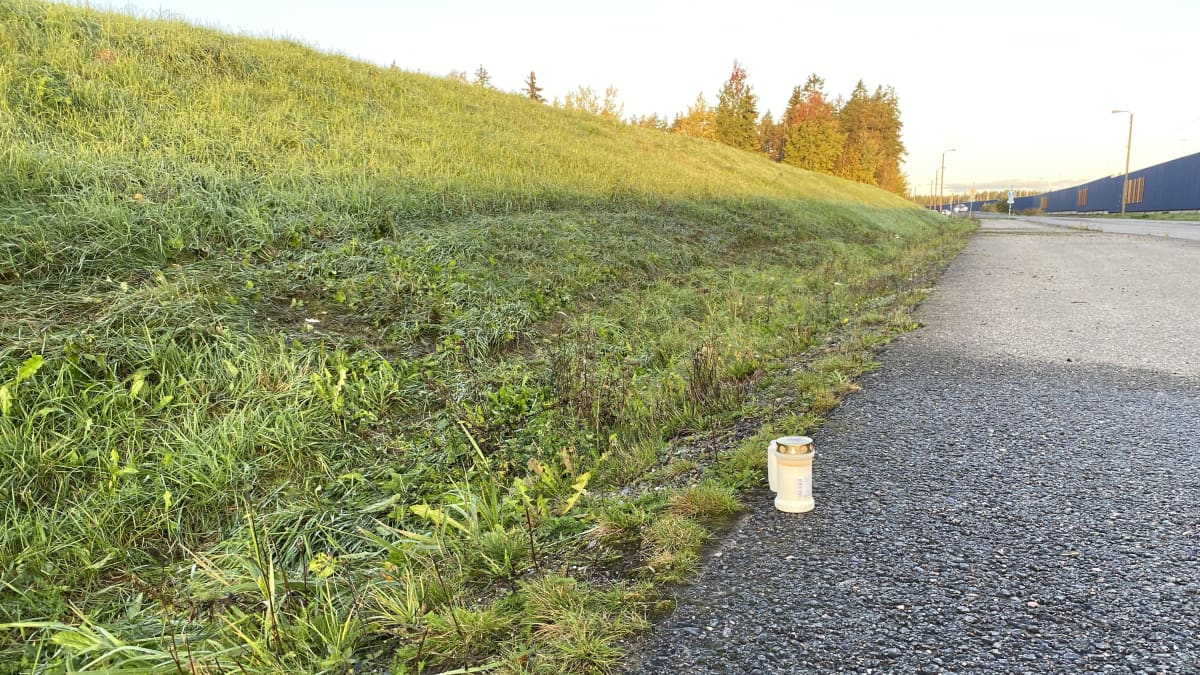 Maantien reunalle on asetettu kaksi palavaa hautakynttilää.