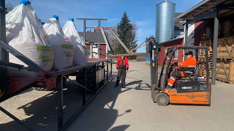 En truck lastar utsäde på en lastbil.
