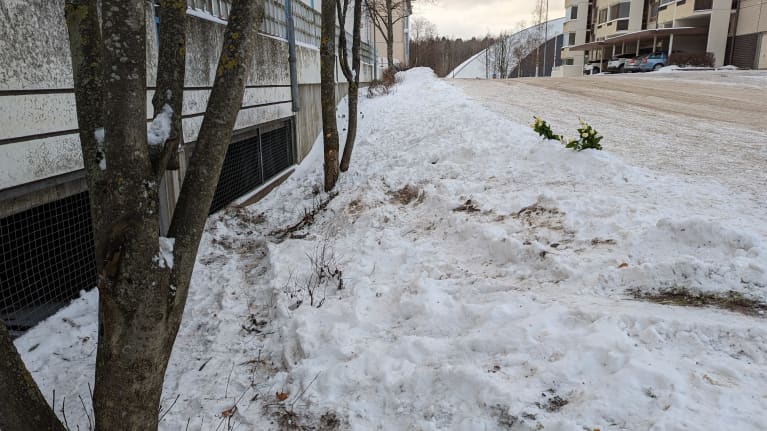 Onnettomuuspaikalla näkyy auton jälkiä seinän ja autotien välissä. Taustalla surukynttilöitä.