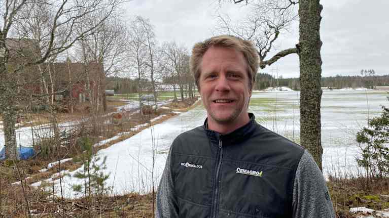 Ung blond jordbrukare i gråblå väst intill åker på sina marker i Kimitoön.