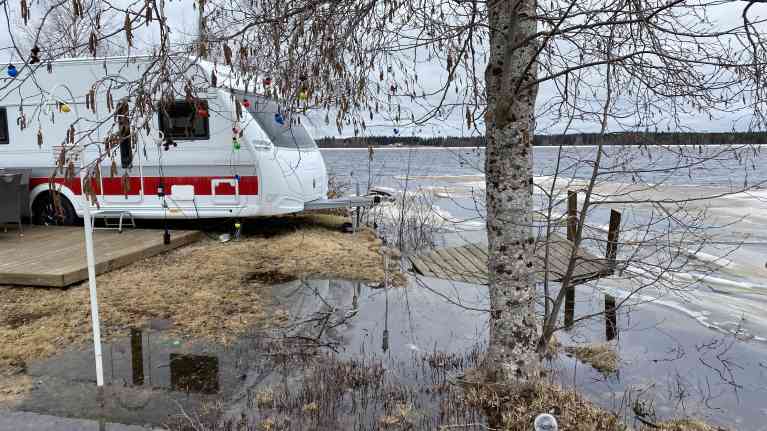 Asuntovaunu tulvivan järven vieressä, laituri osittain on osittain veden vallassa.