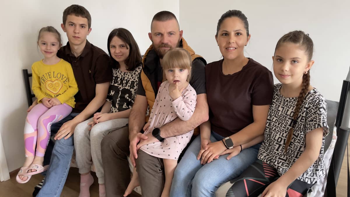 Ukrainasta paennut seitsemän henkinen perhe istuu sängynlaidalla.