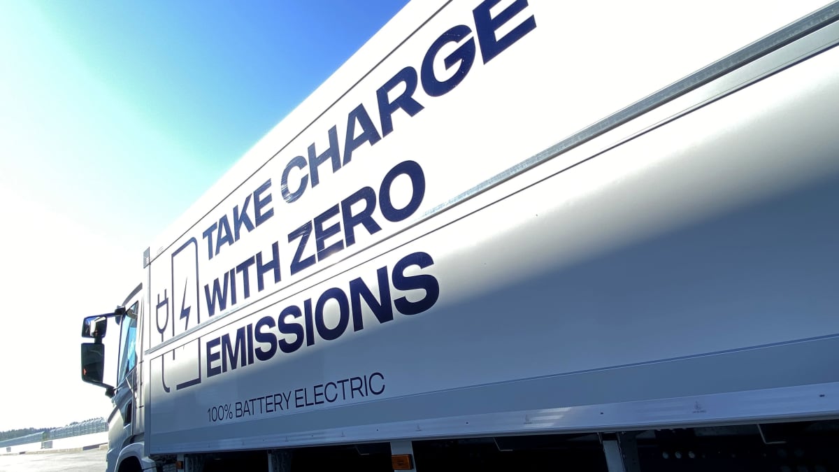 Sähkökuorma-auto kuvattuna sivusta, tavaraosan kyljessä lukee take charge with zero emissions, sininen taivas.