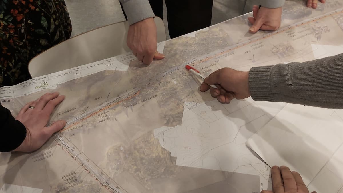 Händer på en planeringskarta över vägbygge.