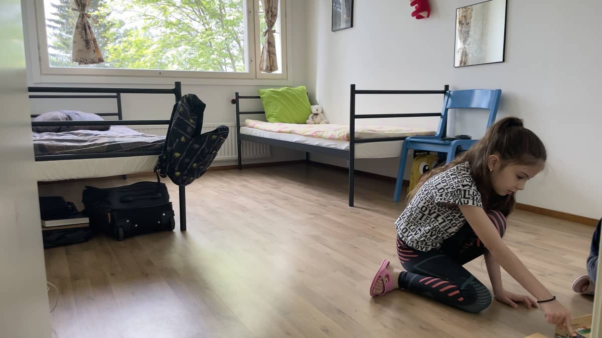 Ukrainalainen tyttö leikkii makuhuoneen lattialla.